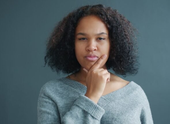 Young woman with hand on chin, looking thoughtful.