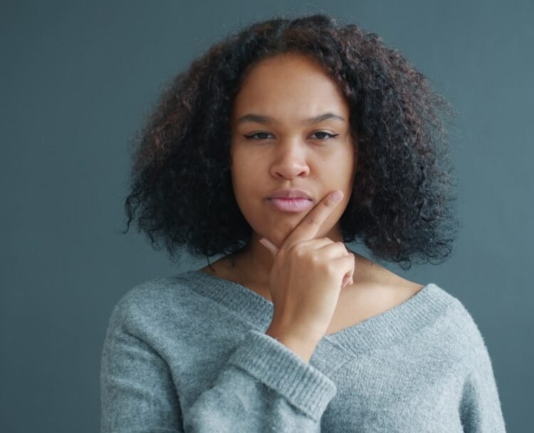 Young woman with hand on chin, looking thoughtful.