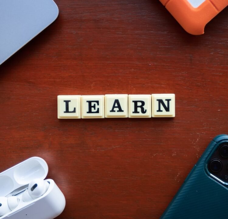 Pessoas usando dispositivos digitais em ambiente de aprendizado colaborativo, com foco em telas e interação.