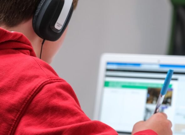 Pessoa estudando em laptop com interface de plataforma de educação online em ambiente moderno e iluminado