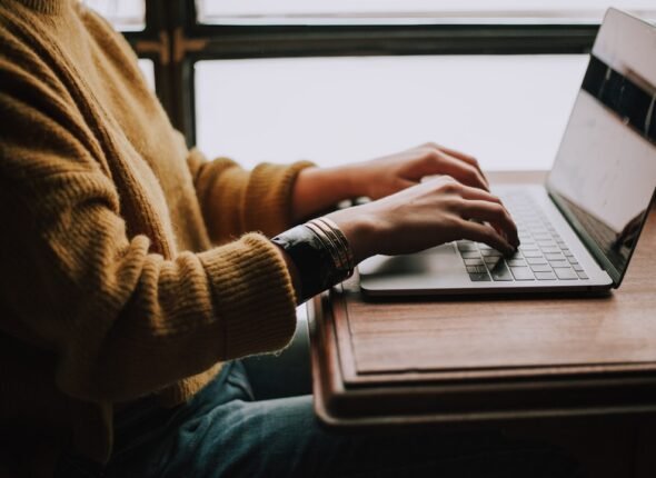 Pessoa estudando de forma autônoma com laptop e materiais de aprendizado digital em ambiente iluminado